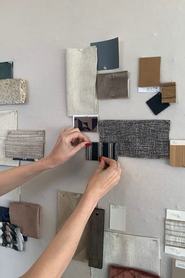 a woman pinning fabric samples to an interior design moodboard