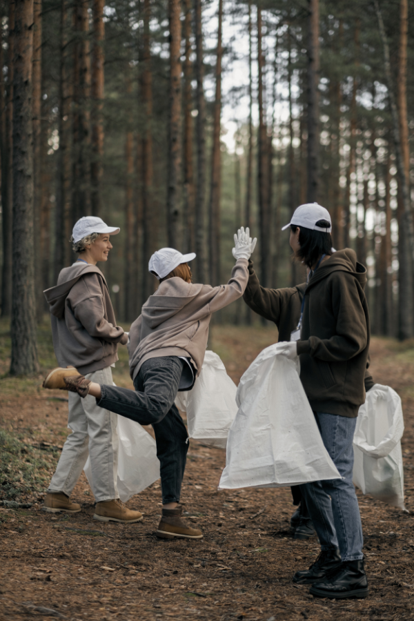 women volunteering by picking up trash in a forest, demonstrating benefits of volunteering