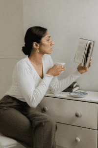 woman sitting at a vanity with a cup of tea, reading one of the best books about organization