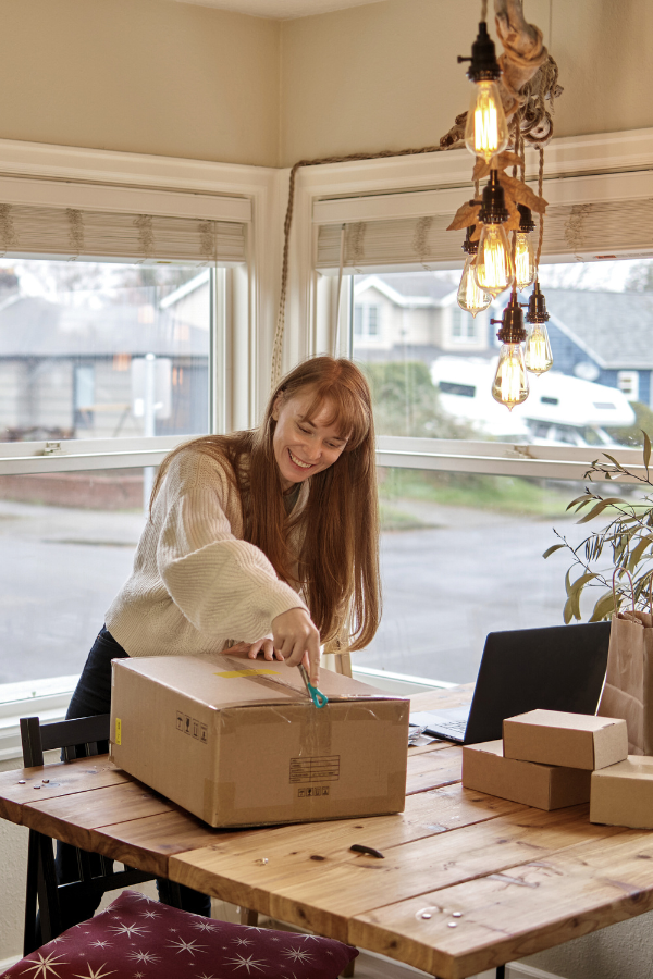woman opening an art subscription box in front of her window