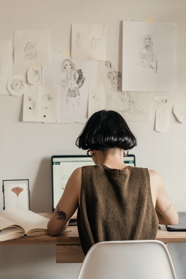 woman with short black hair sitting at her computer building an online art portfolio