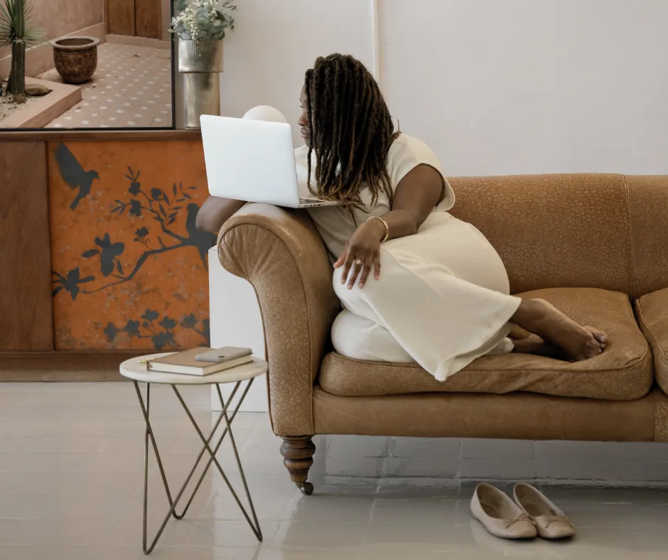 a travel agent working on her couch with her computer