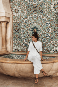 tile patterns behind a woman sitting on a fountain