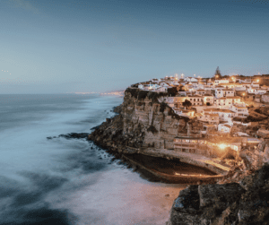 a photo of the coast of Portugal with homes along a cliff; part of our guide to buying property in Portugal