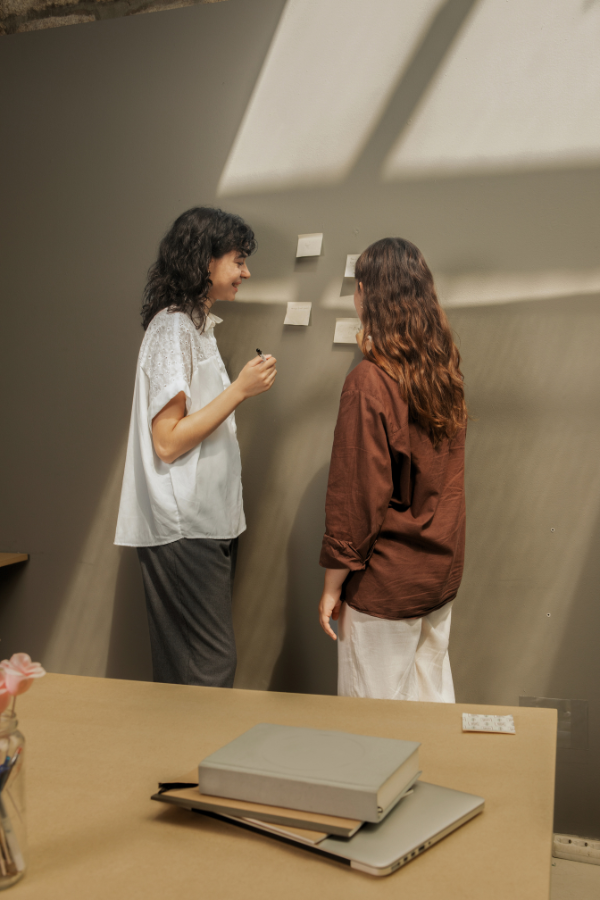 two designers standing at a wall placing post-it notes on the wall