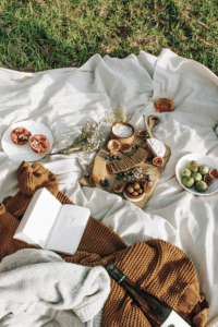 a picnic with summer side dishes and a blanket with books