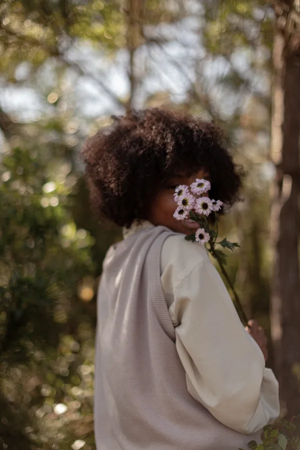 a woman hold flowers to plant in summer in front of her face while outdoors