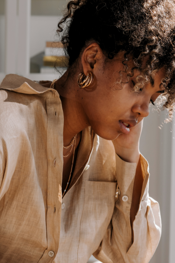 woman wearing gold jewelry and a beige linen shirt