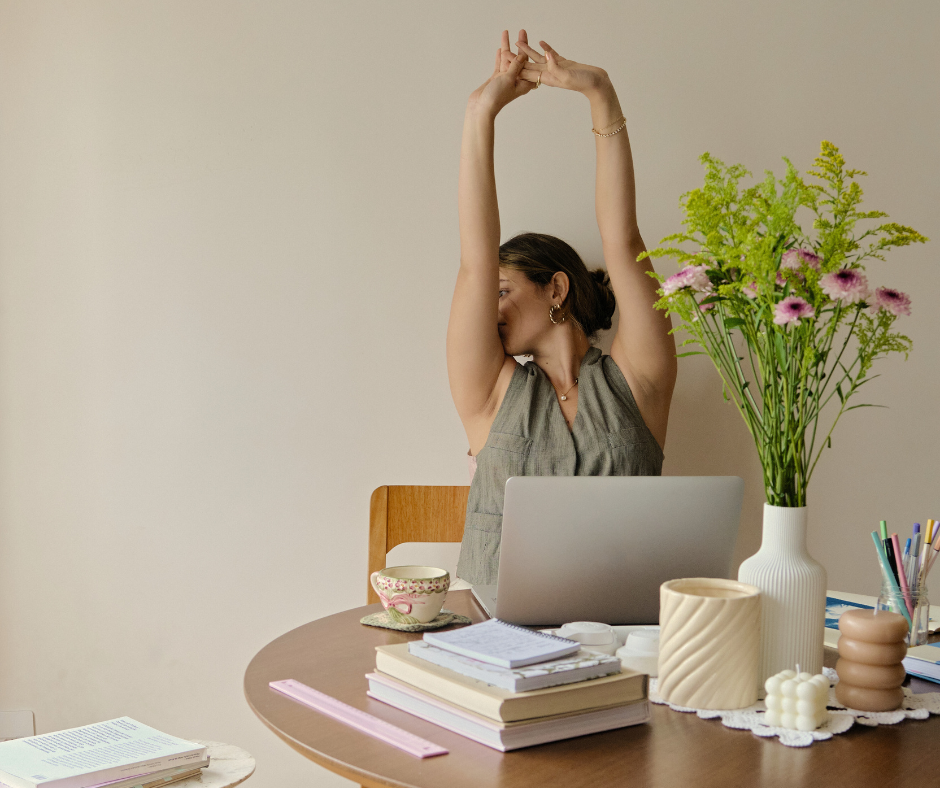 a woman at her desk stretches her arms above her head