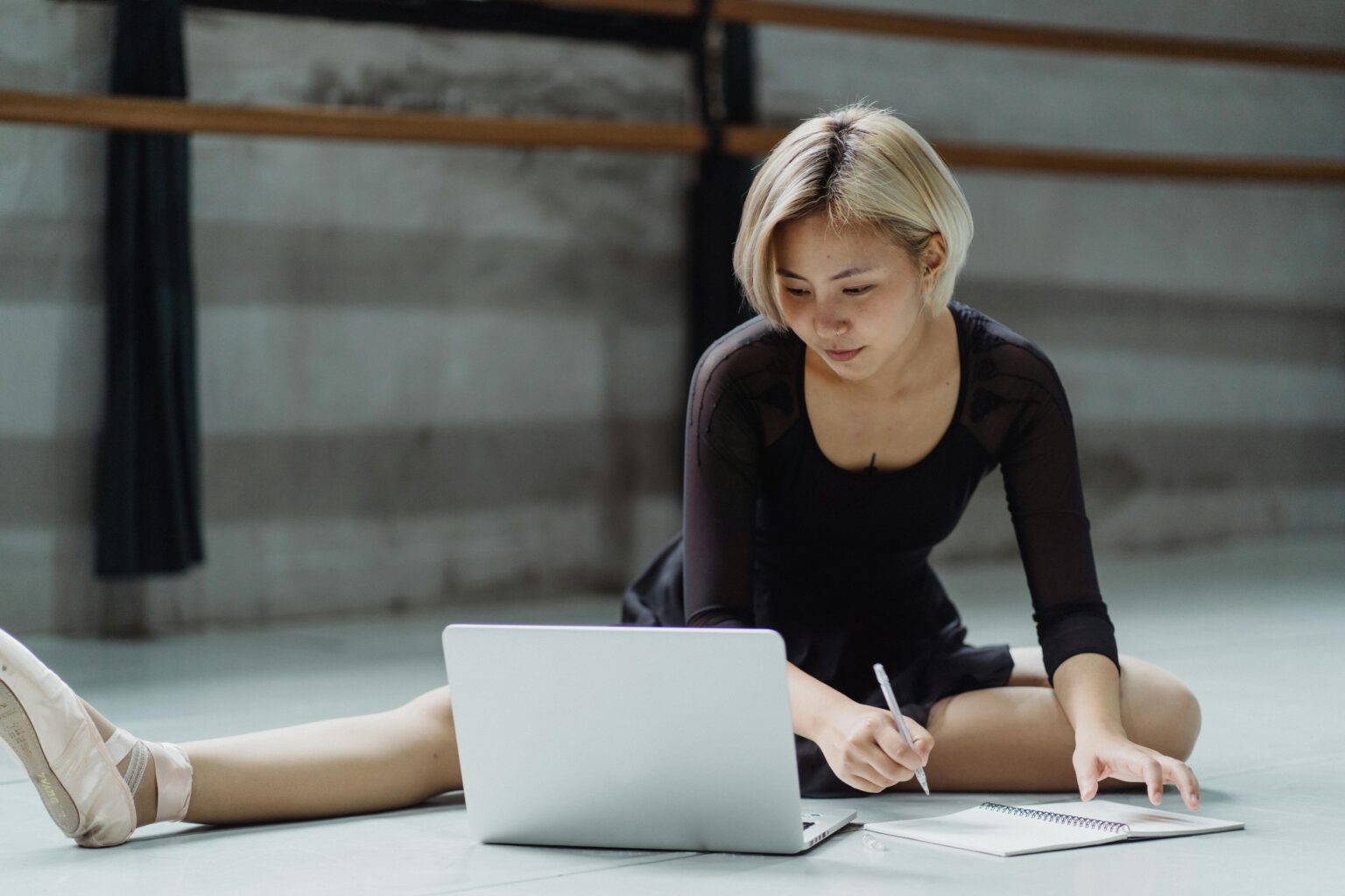 Woman working on a yoga mat, stretching in front of her laptop