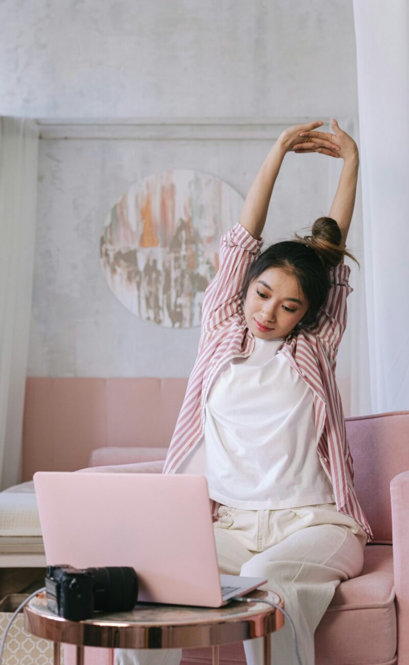 A woman stretching in front of her laptop