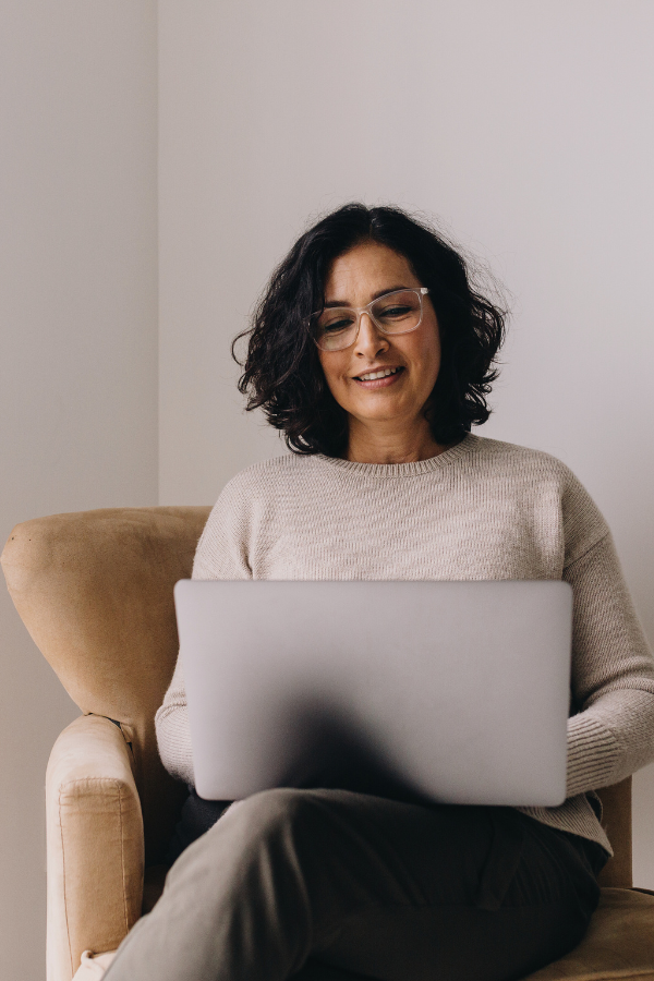 a woman sits in a chair with her laptop