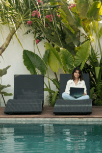 woman sitting on a lounge chair with her laptop by the pool