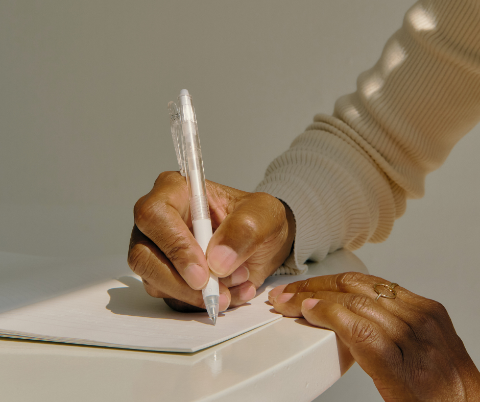 a woman writes in a notebook at a table