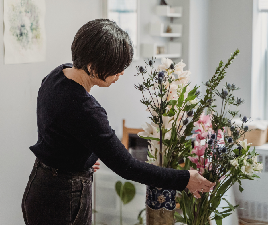 a woman creates a floral arrangement in her home