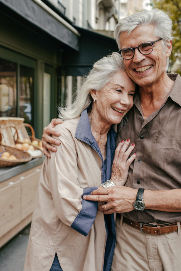 an older couple embraces as they walk down the street