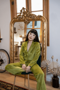 a woman in a gorgeous green suit poses in front of a mirror