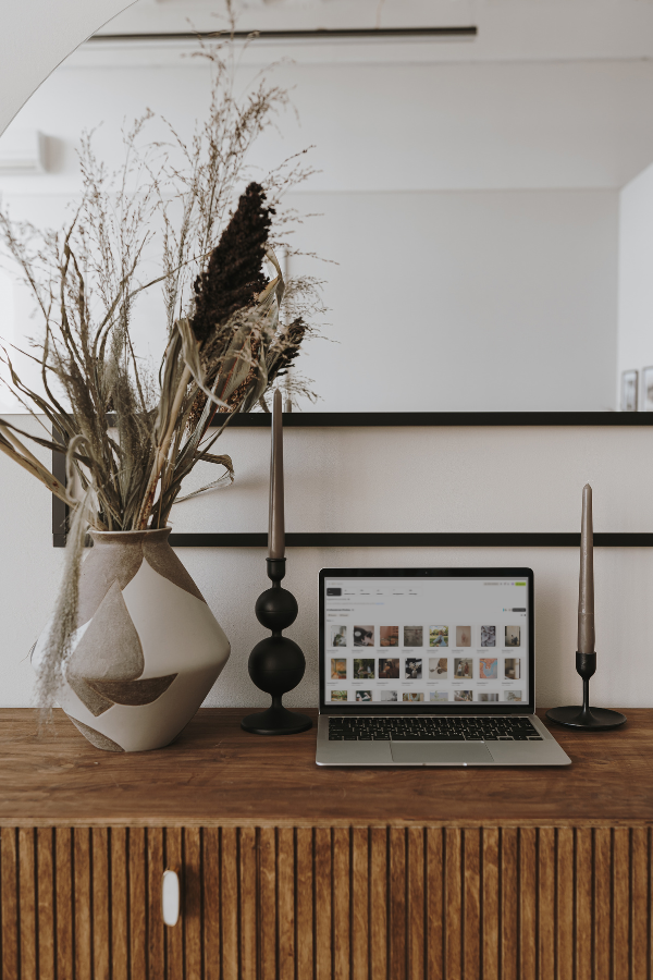 laptop on a sideboard surrounded by decor