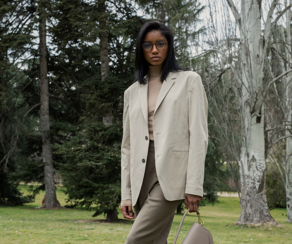 a woman wearing trousers, a turtleneck, and a blazer in the outdoors