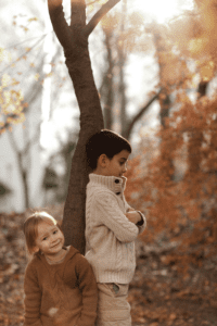 two kids in a sibling rivalry stand outdoors during fall