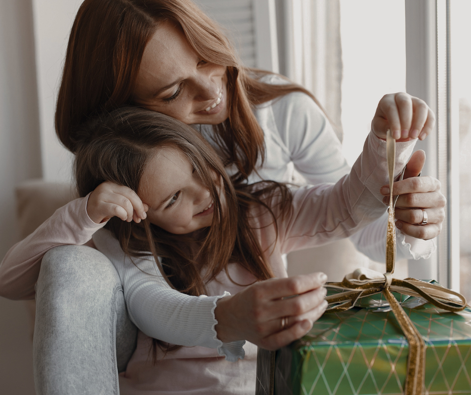 a mom and daughter open a present together