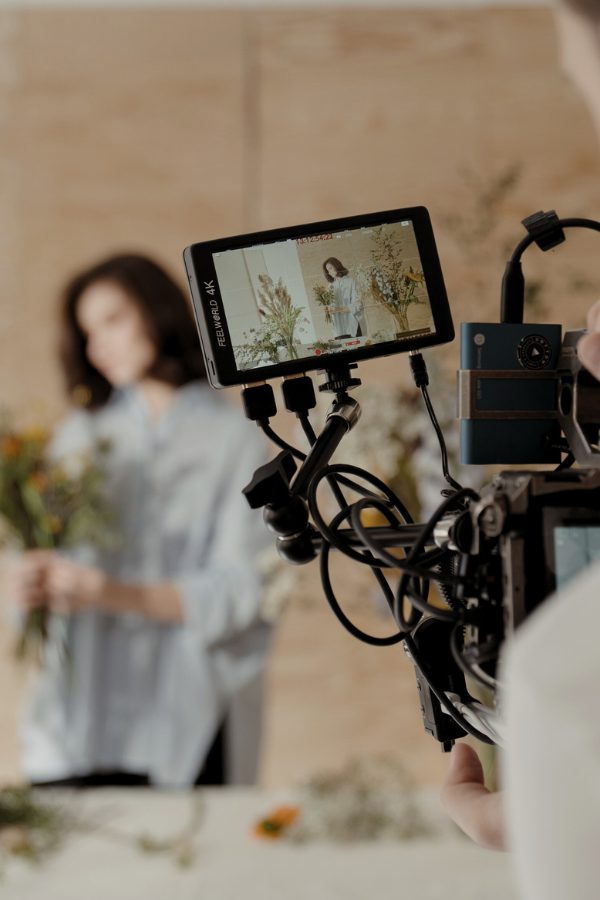 person filming a woman making floral arrangements