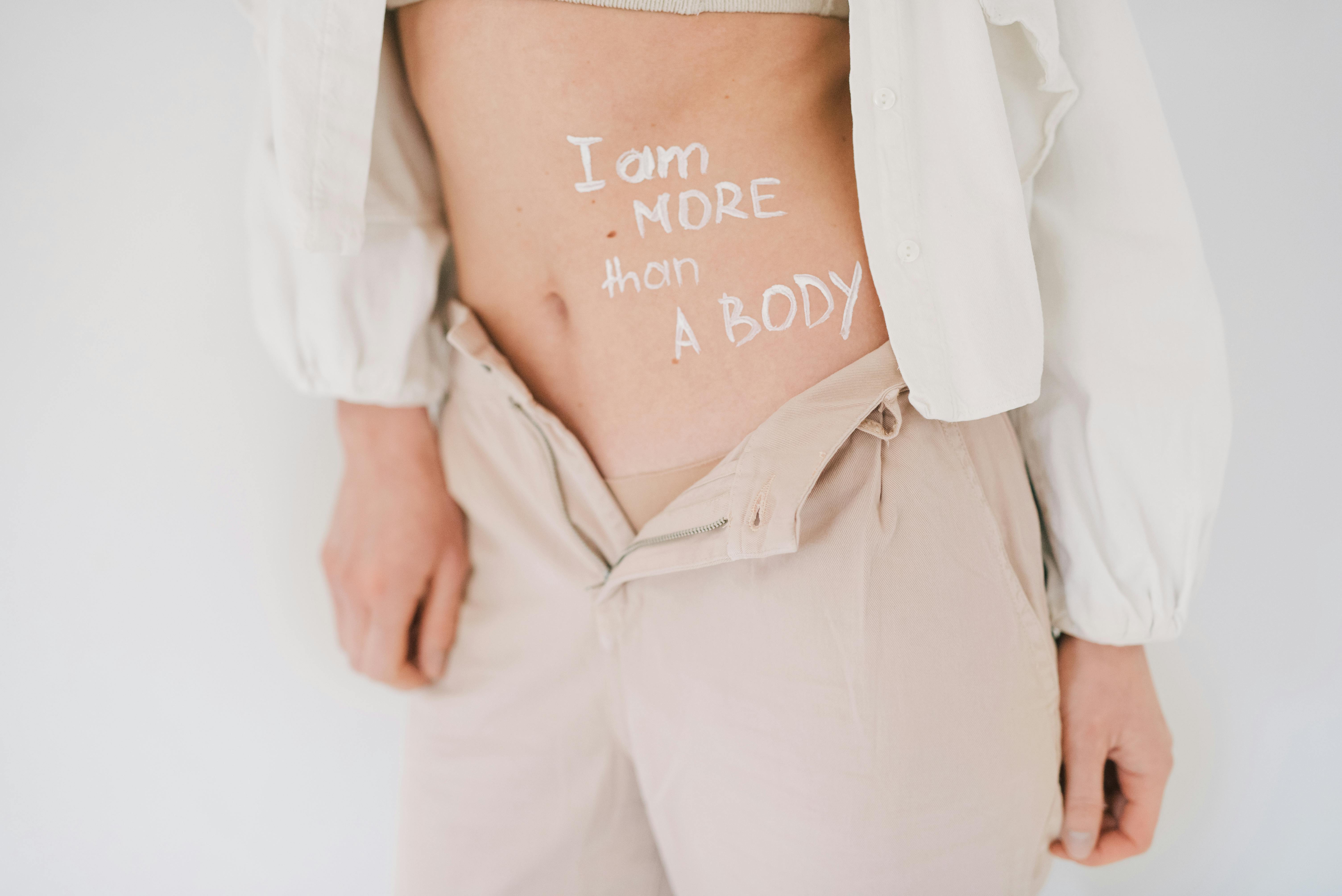 A close-up image of a person's torso with the message 'I am MORE than A BODY' written across their waist.