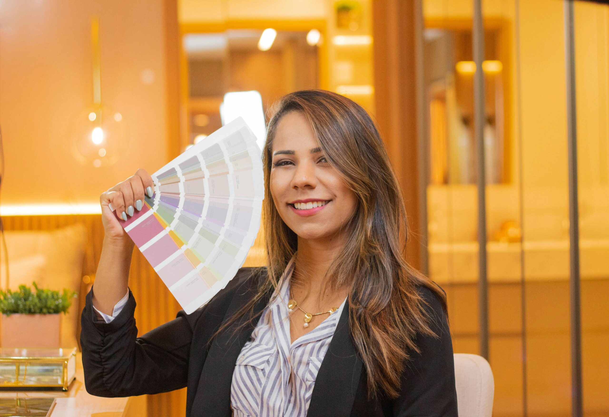 Woman holding a color palette in a stylish interior setting.