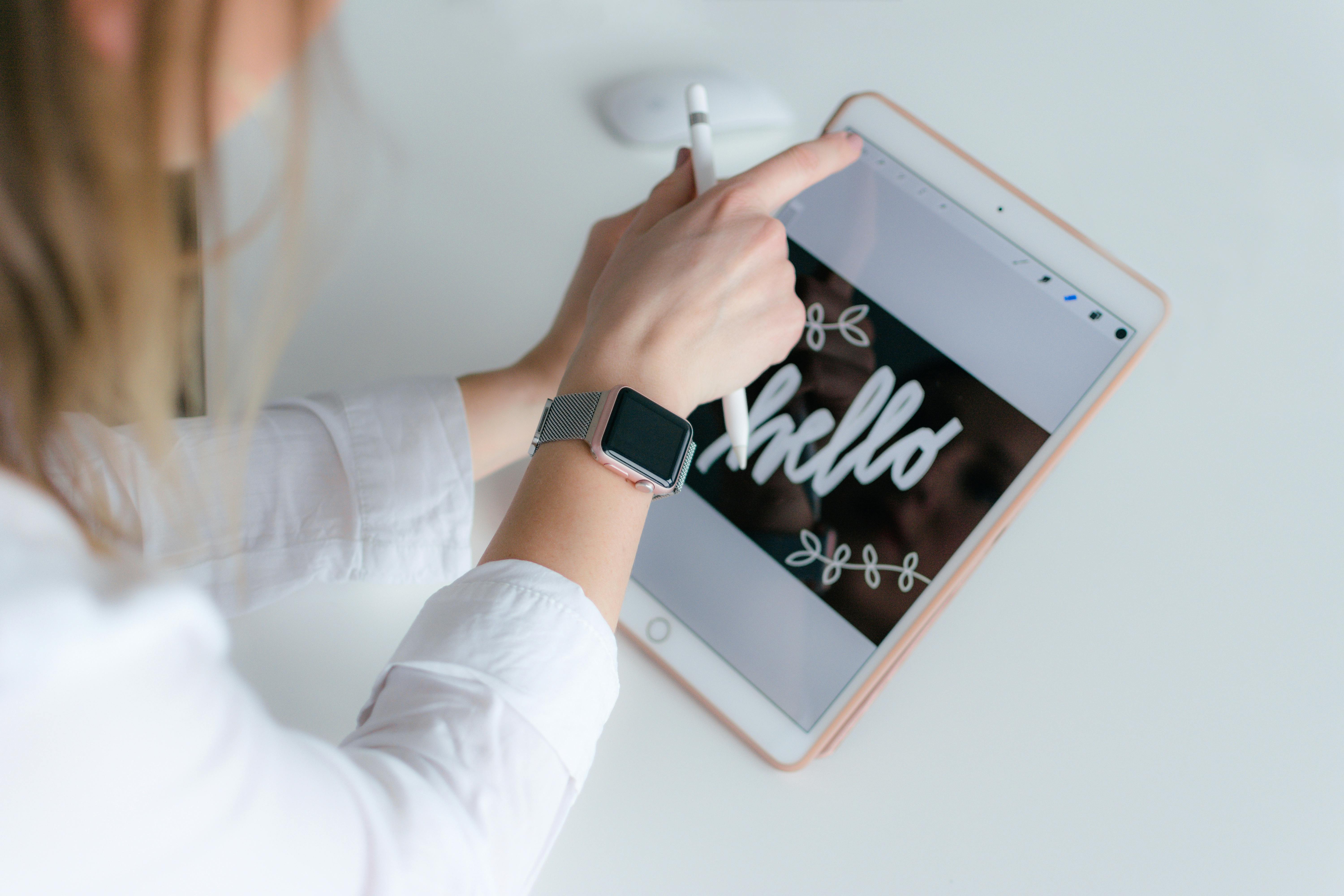 A person drawing on a tablet with a stylus, displaying handwritten text