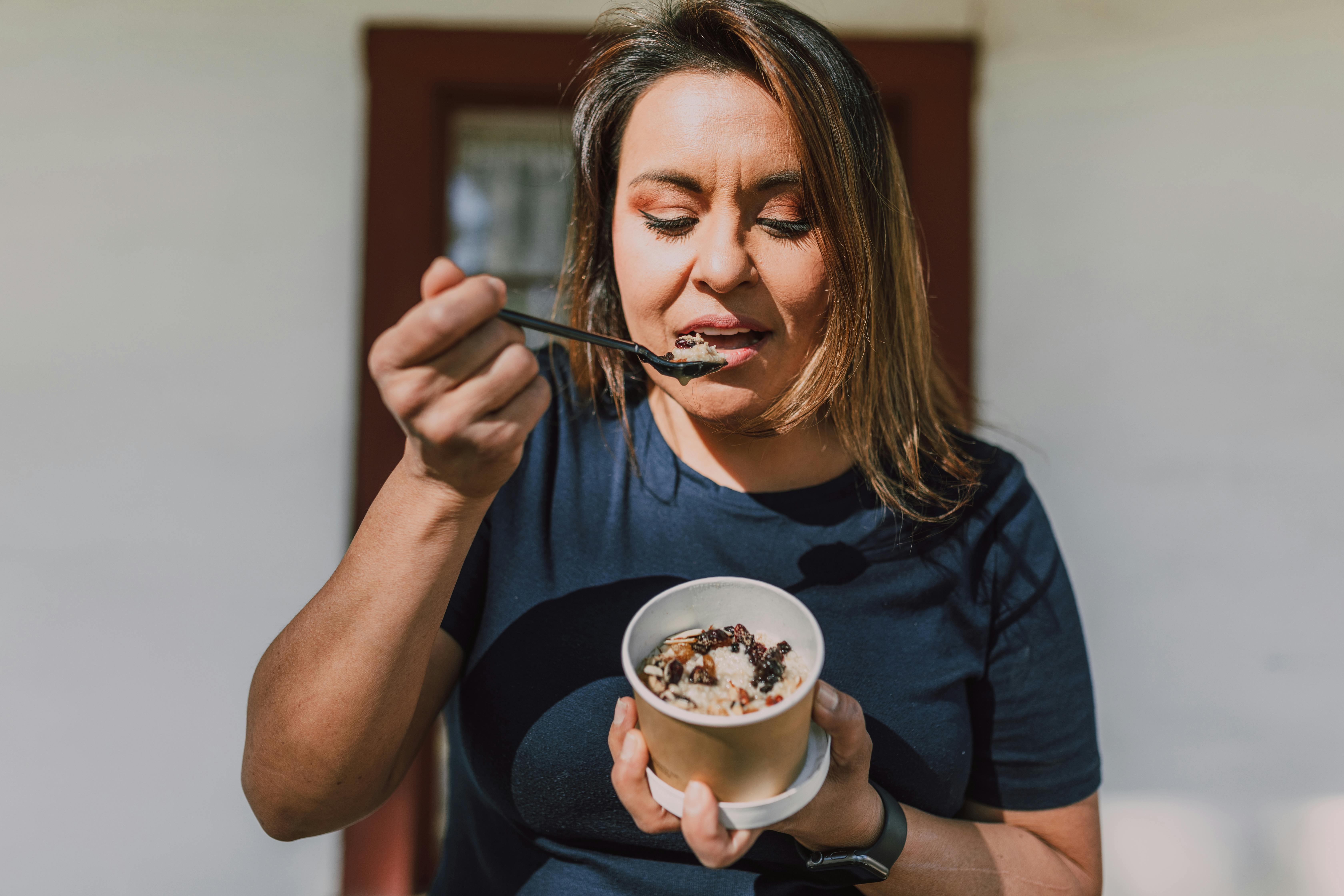 A person enjoying a dessert outdoors with a spoon in their hand.