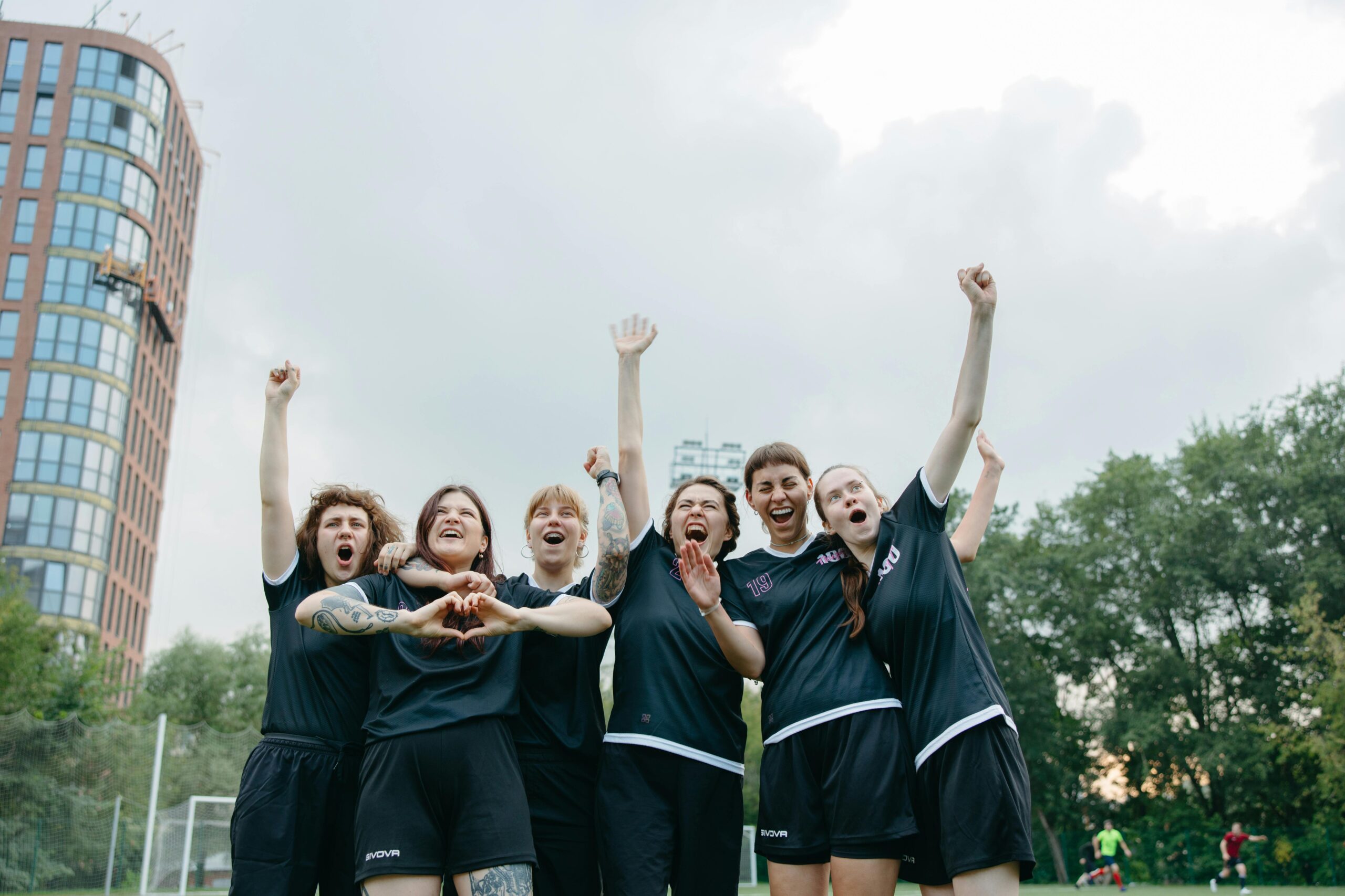 A group of excited female soccer players celebrating on the field.