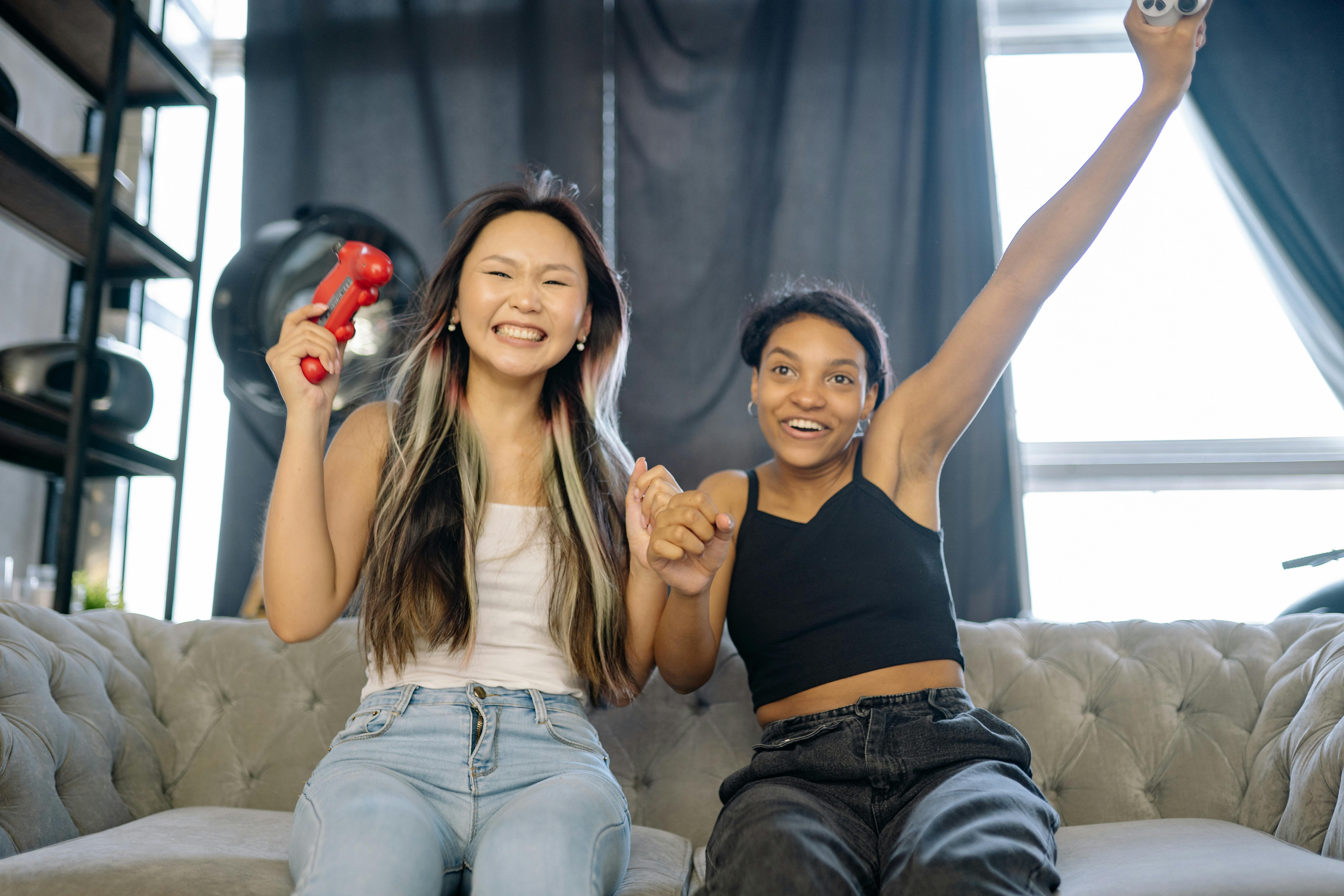 Two friends celebrating while playing video games on a couch.