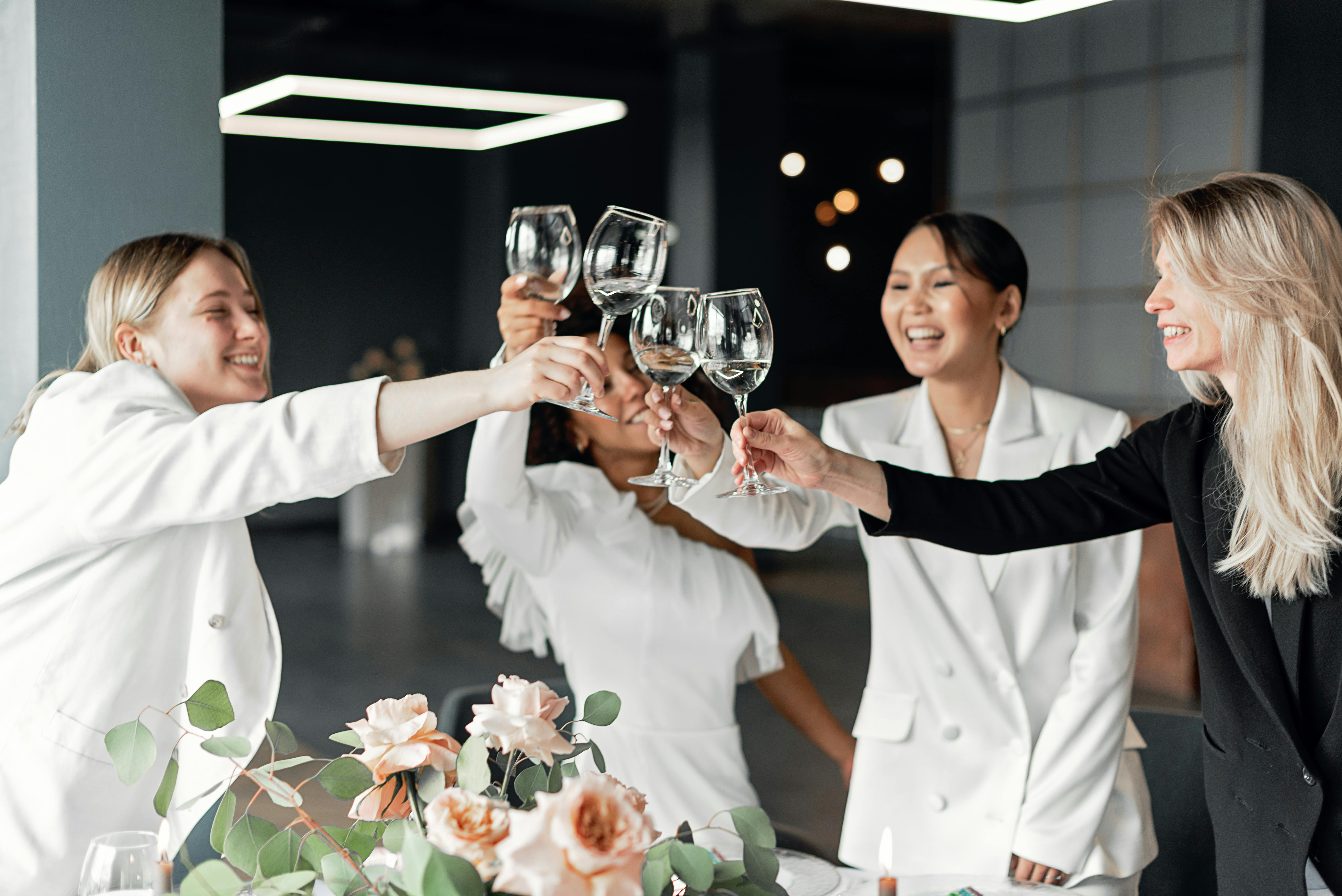 A group of women toasting with glasses of liquid, celebrating together.