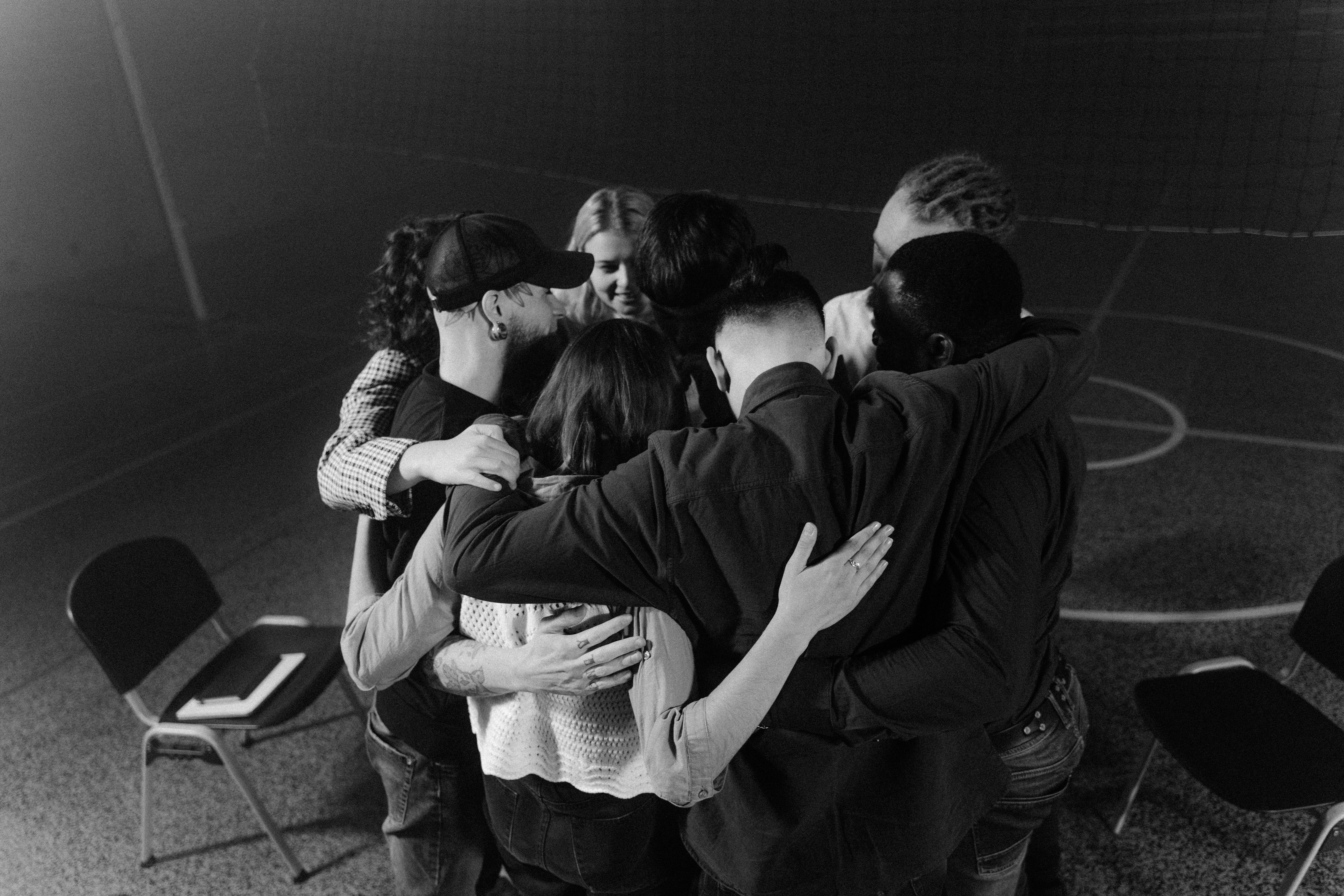 A group of people in a close embrace, captured in black and white.