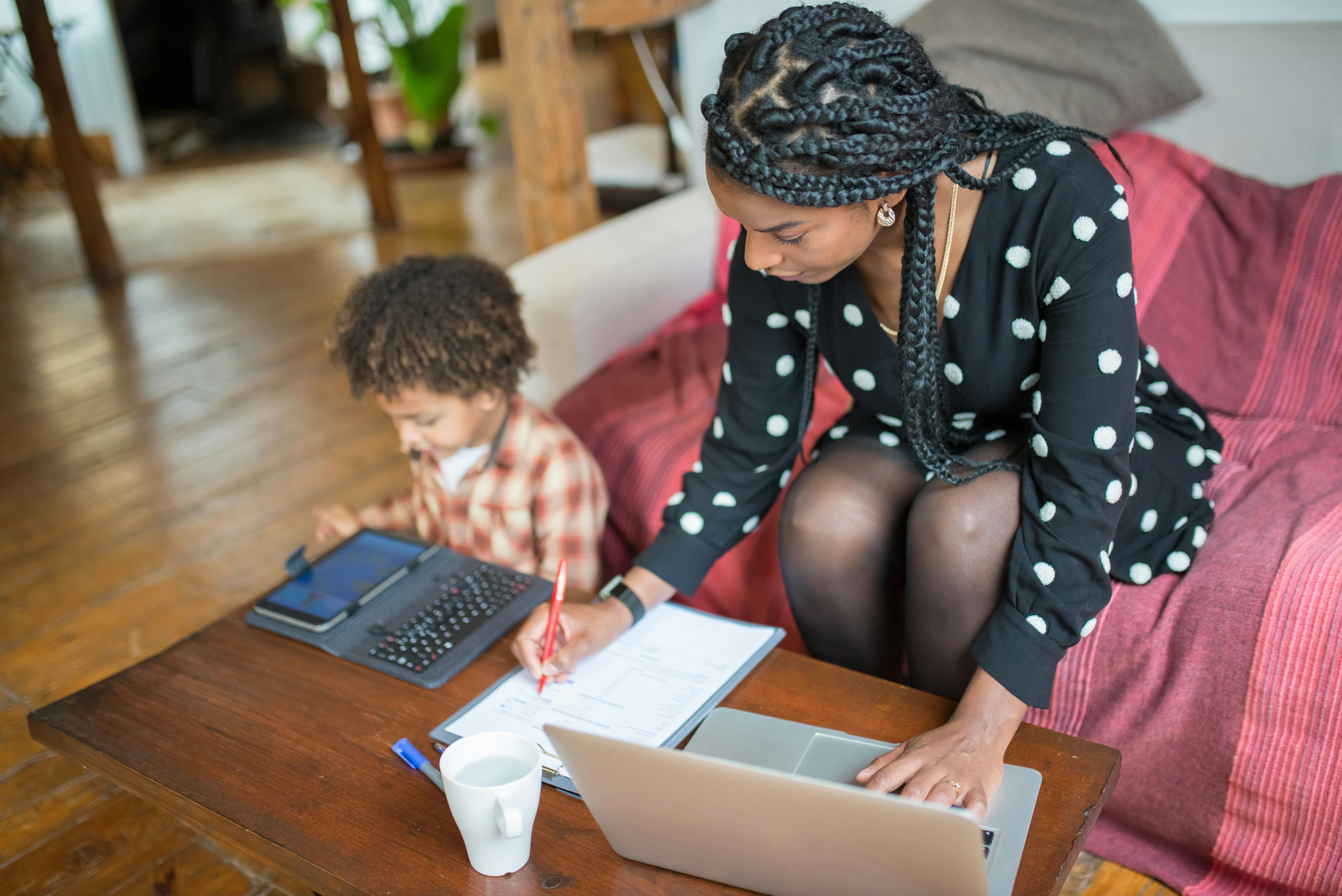 A mother and her child working together at a table in a cozy living space.