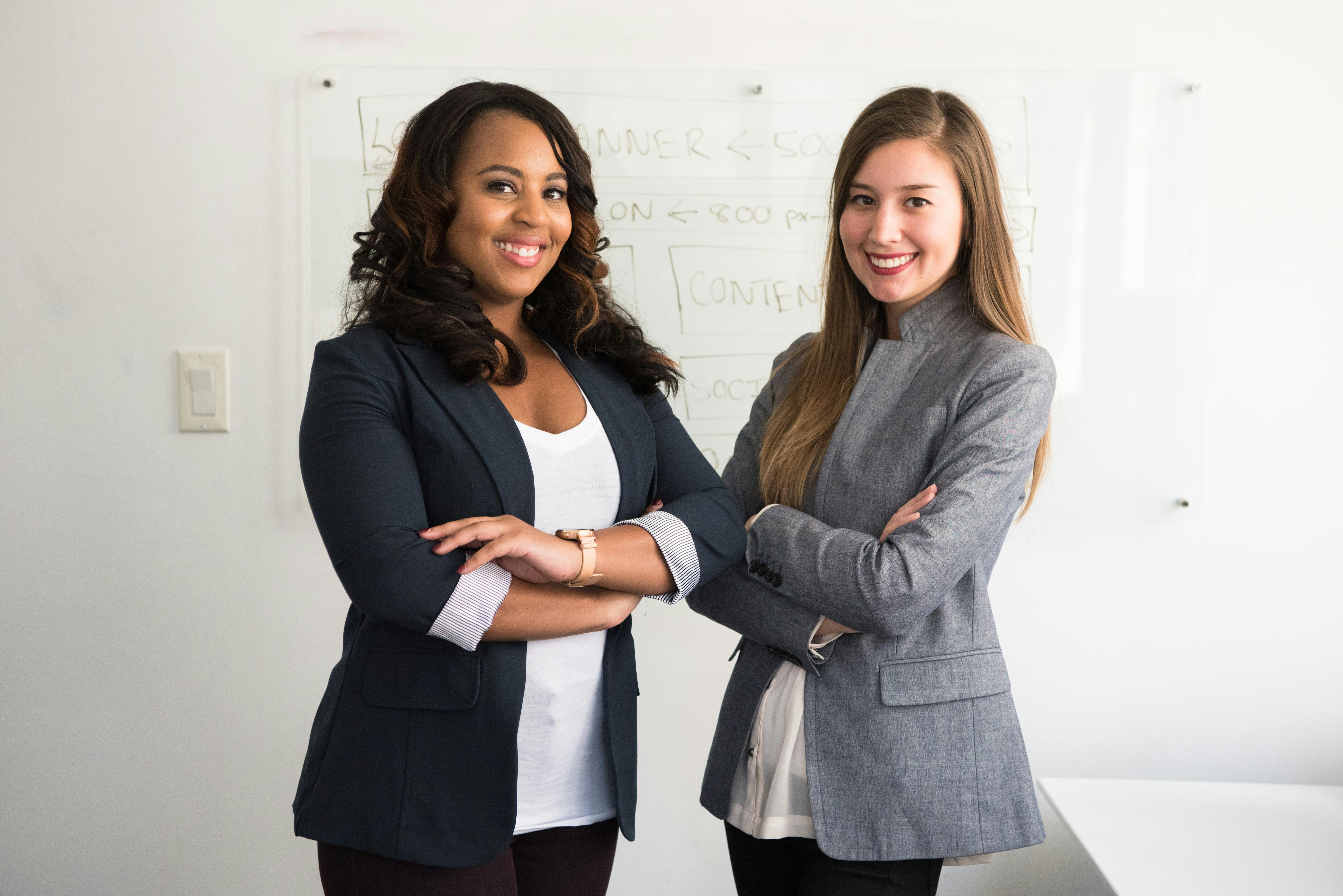 Two professional women standing confidently in an office setting.