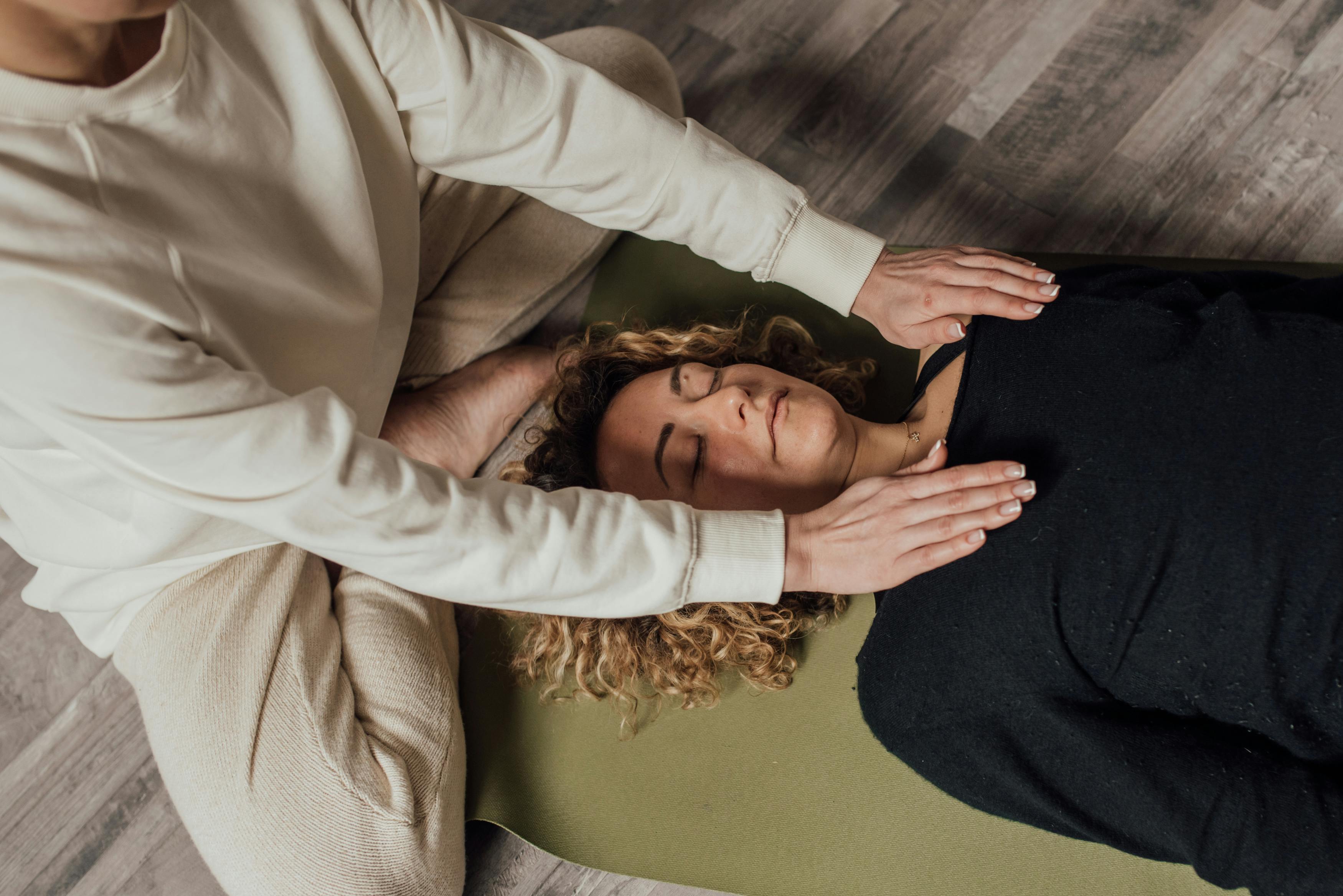 A person receiving a Reiki session with hands placed on their chest.