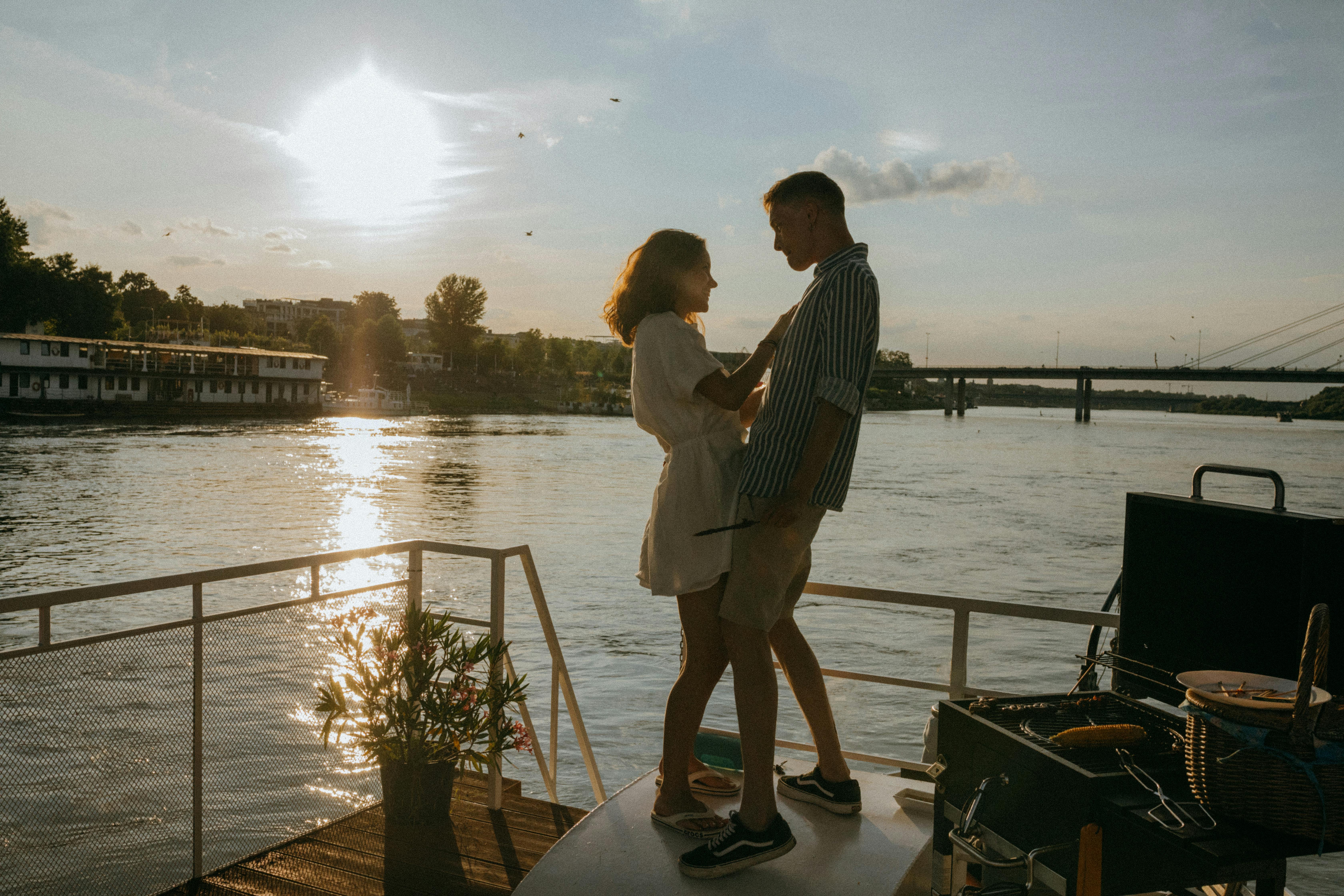 A couple sharing a romantic moment on a boat during sunset.