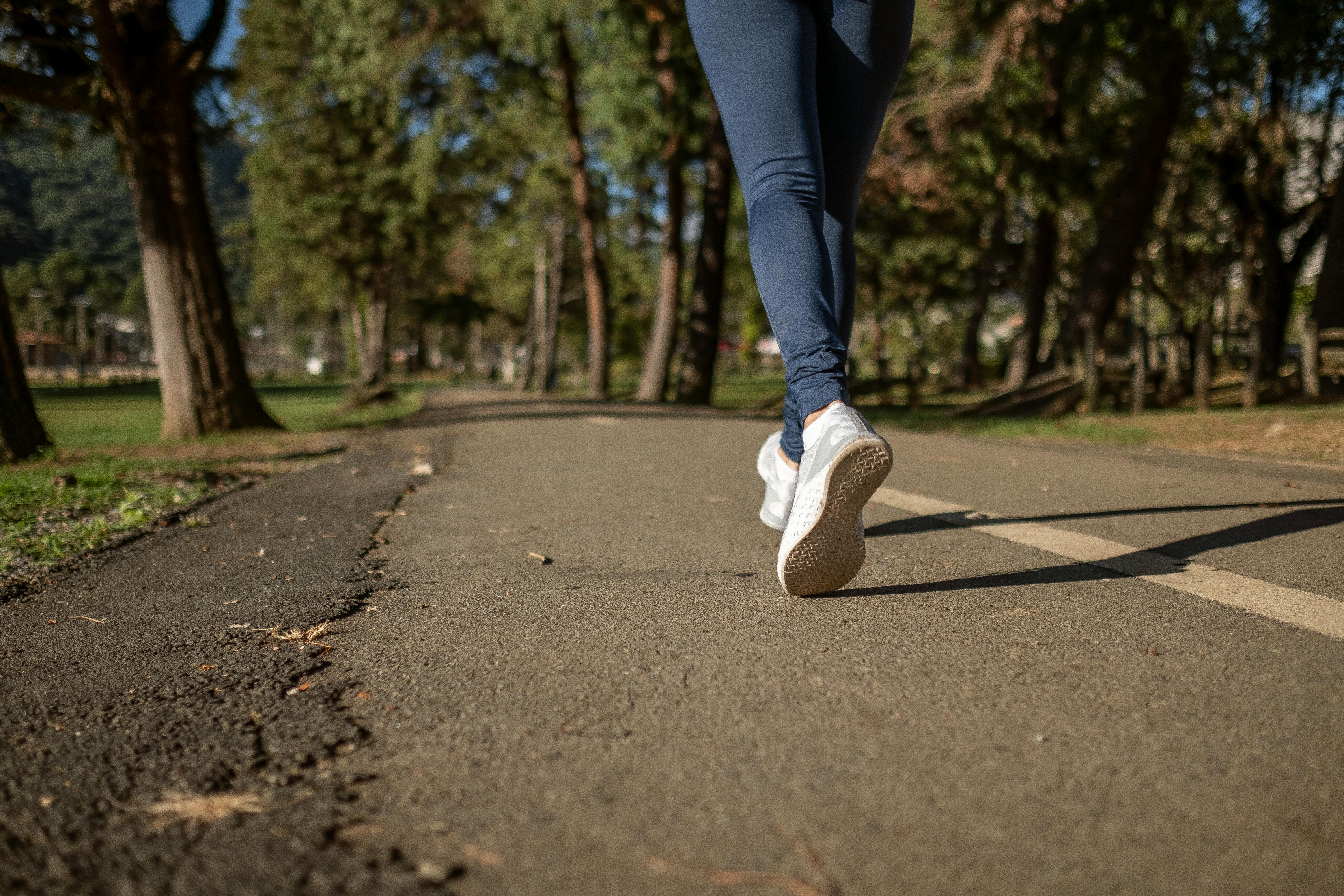 A person running on a path surrounded by trees.