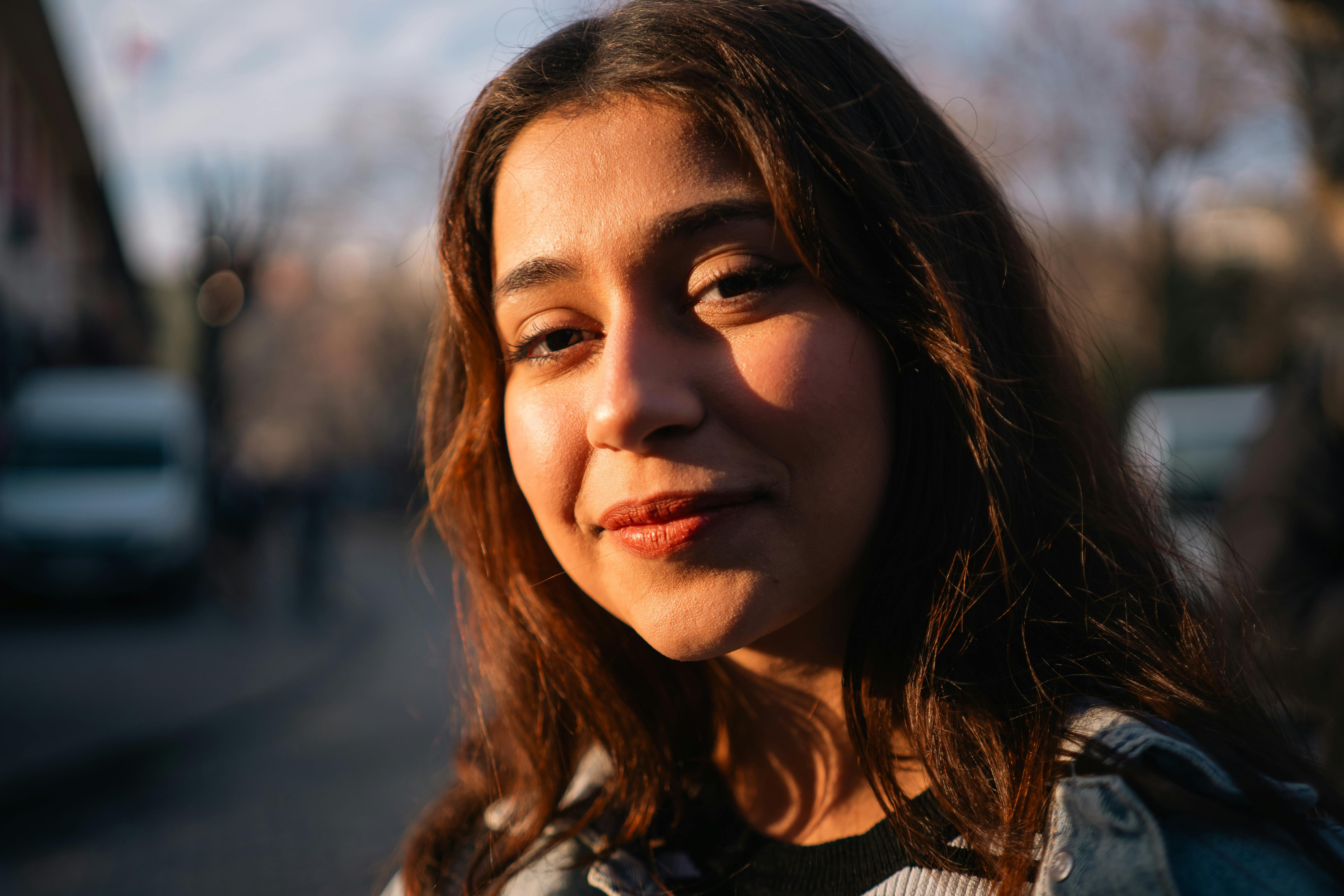 Close-up of a smiling young woman with long hair in soft evening light.