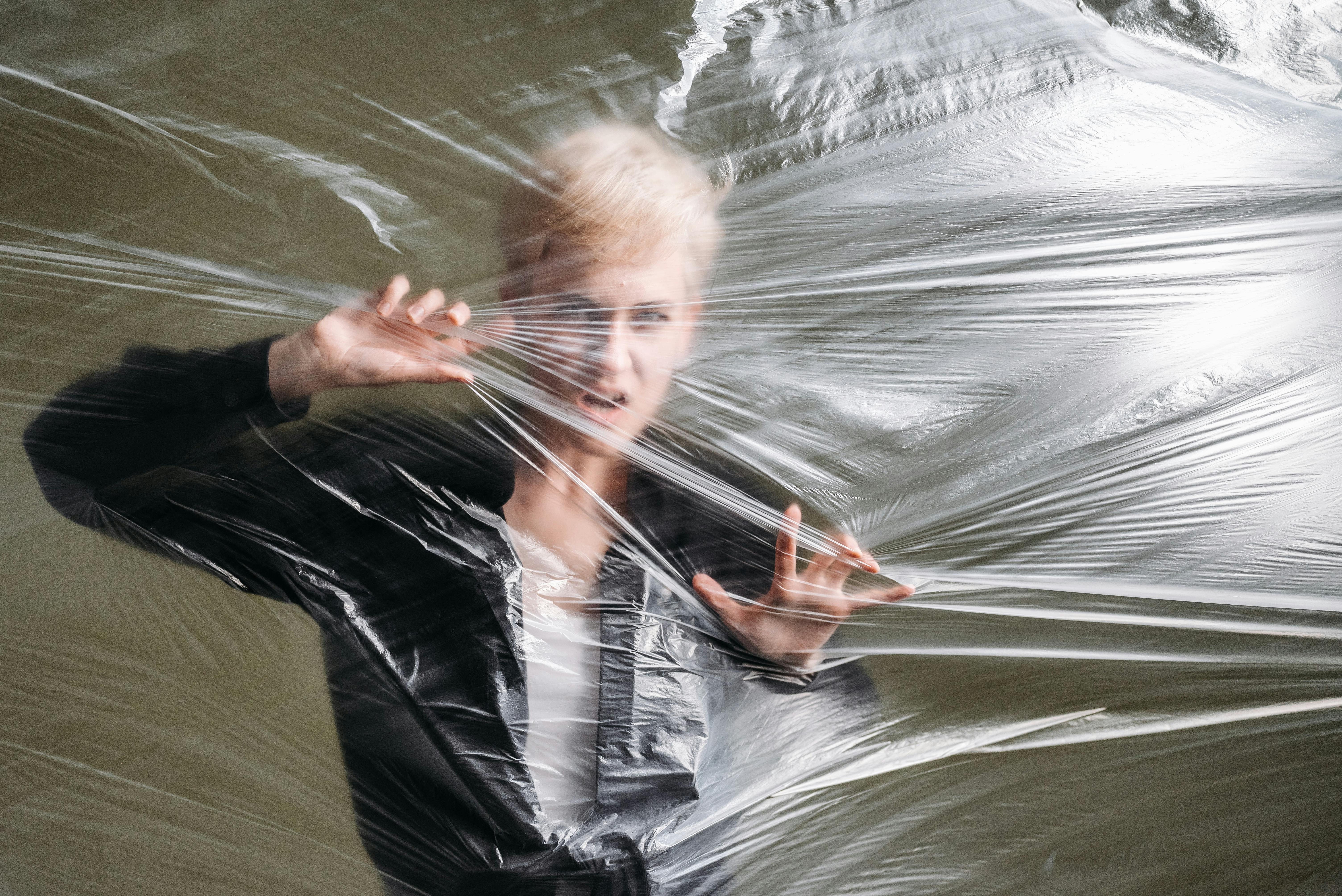 A person struggles behind a sheer plastic wrap.