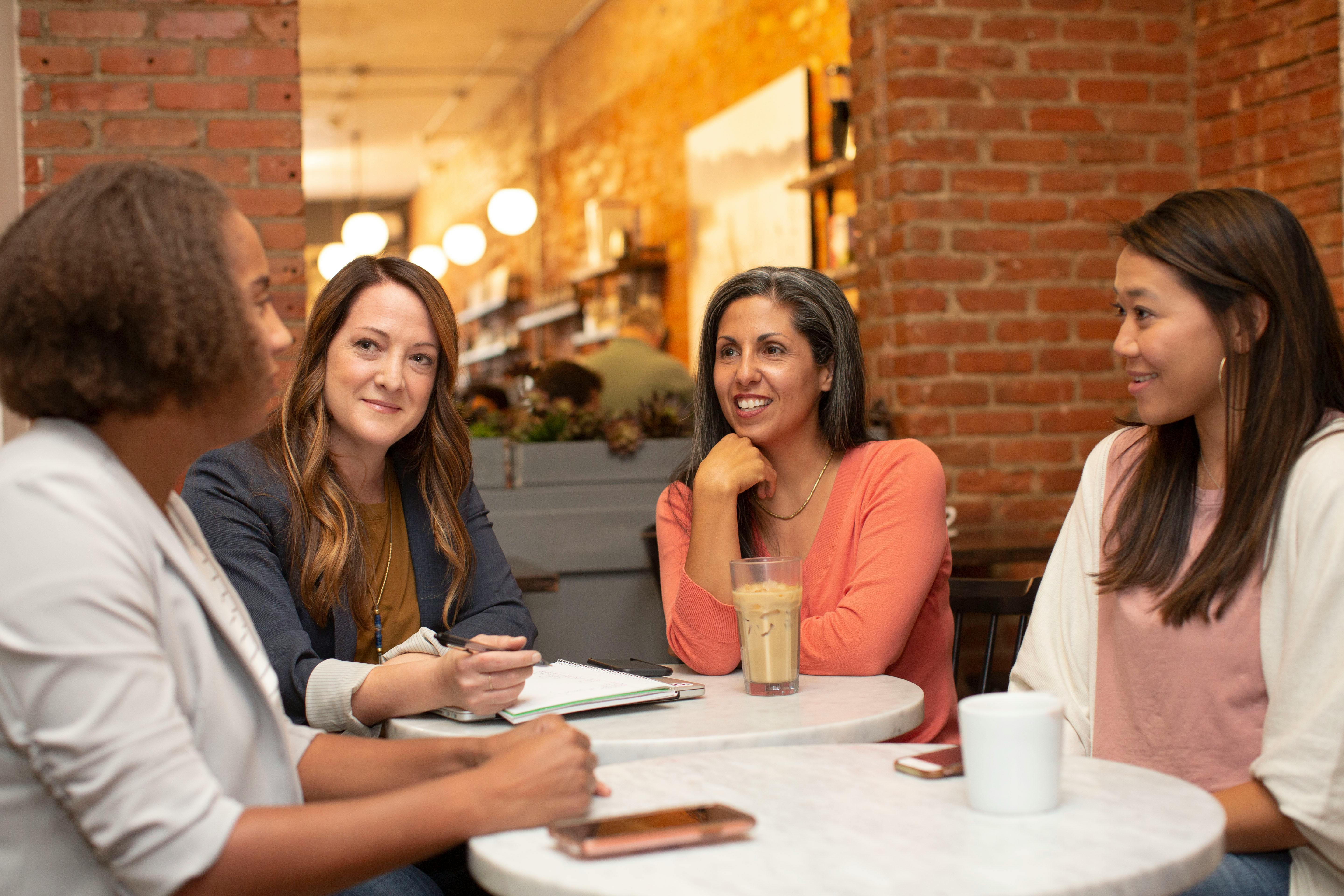 Four women engaging in a conversation at a coffee shop.