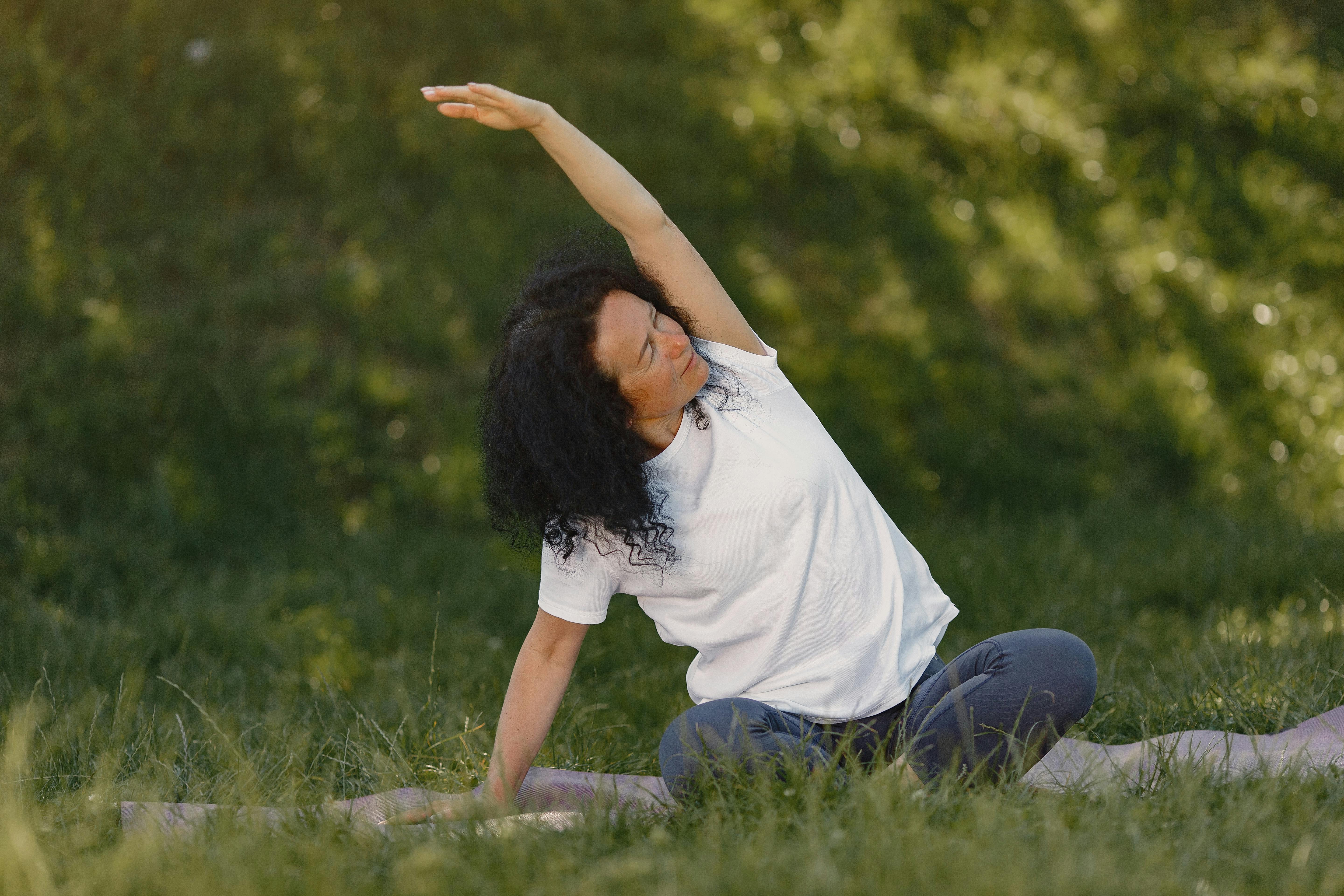 A woman practicing yoga in a grassy field.