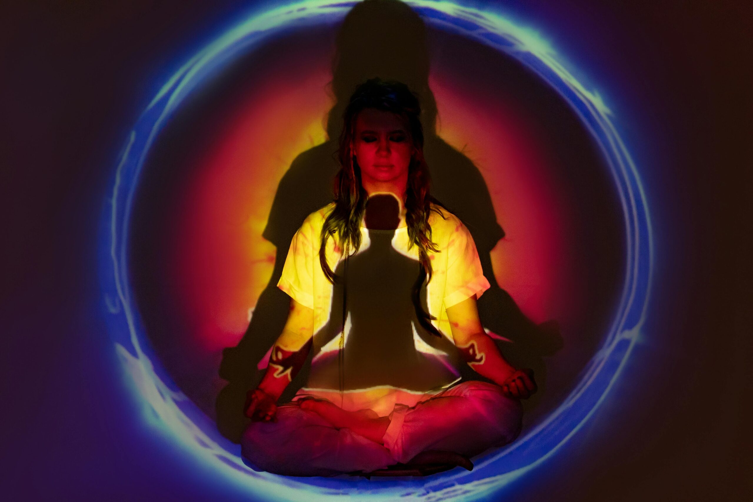 A person meditating with colorful light projections around them