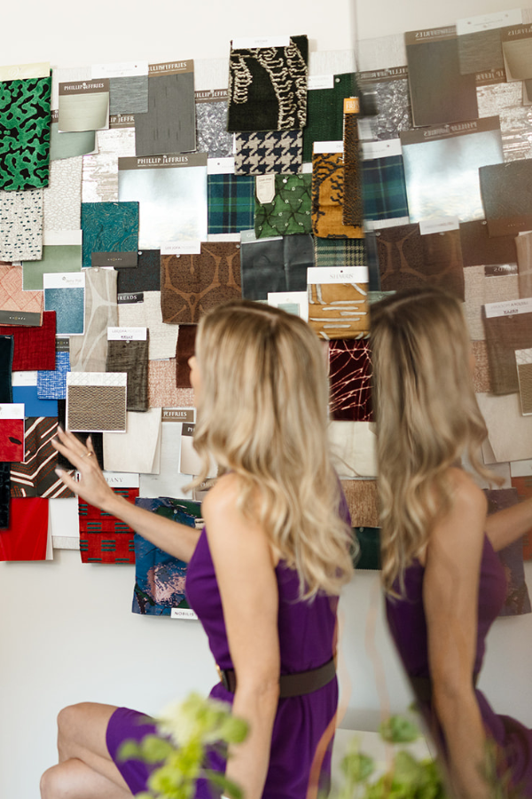 A designer examining a wall of fabric samples in a studio