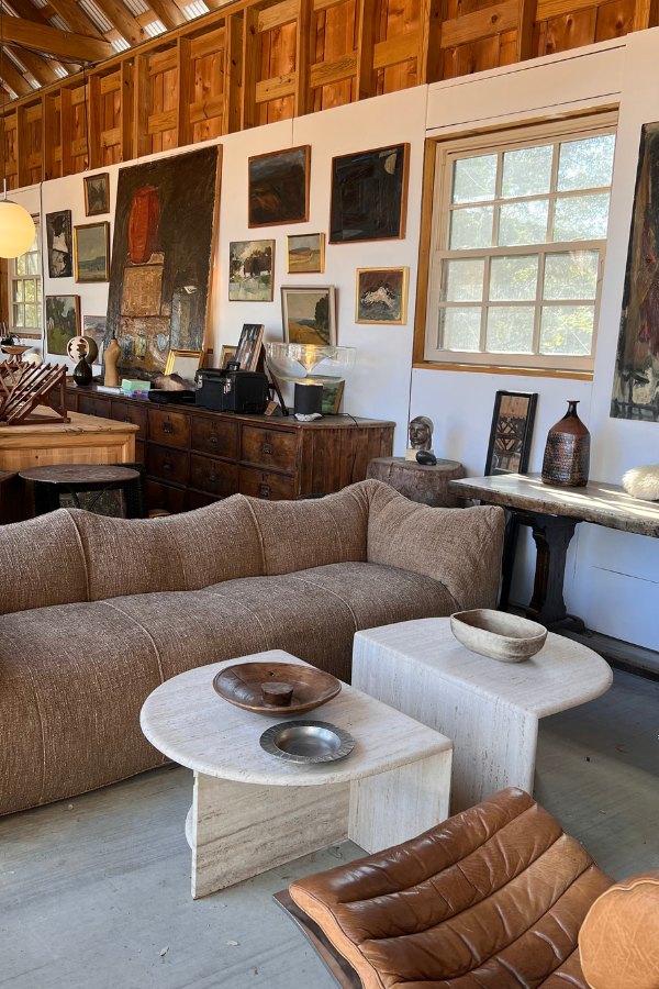 Barn interior displaying vintage furniture, abstract paintings, and sculptural decor arranged in a curated seating vignette at a Round Top venue.