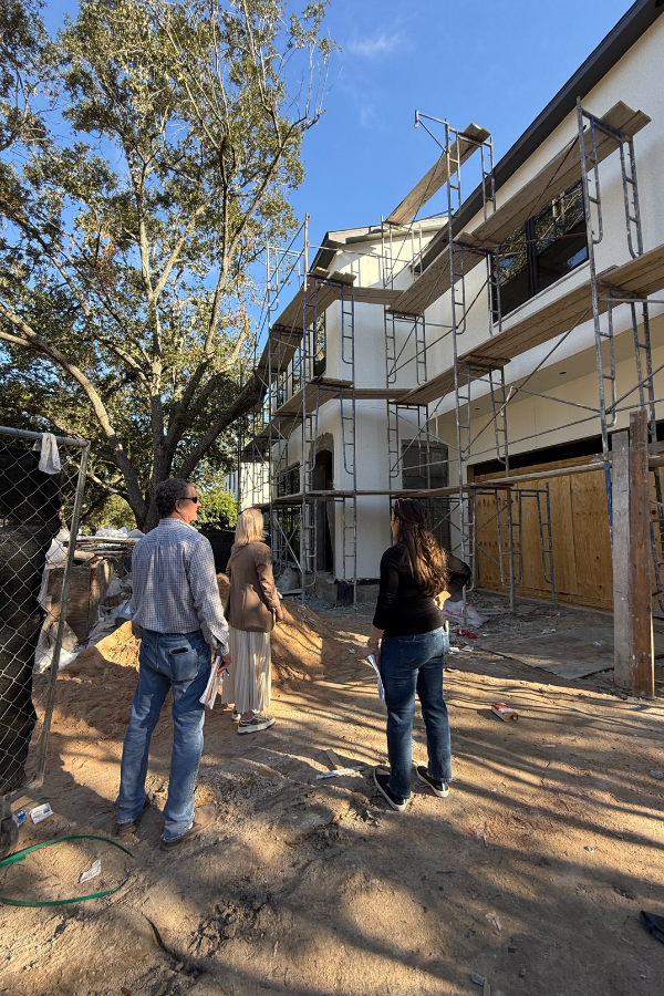 Interior designers walking through a home during early construction framing, reviewing layout and structural elements of a renovation project.