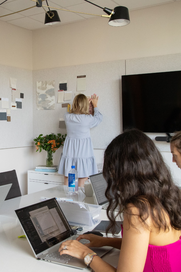 three designers gathered together working on mood boards and on their laptops