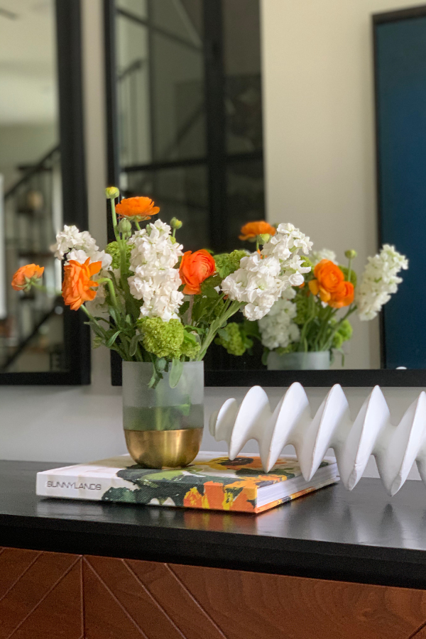 a table with a book, flowers, and decorative object