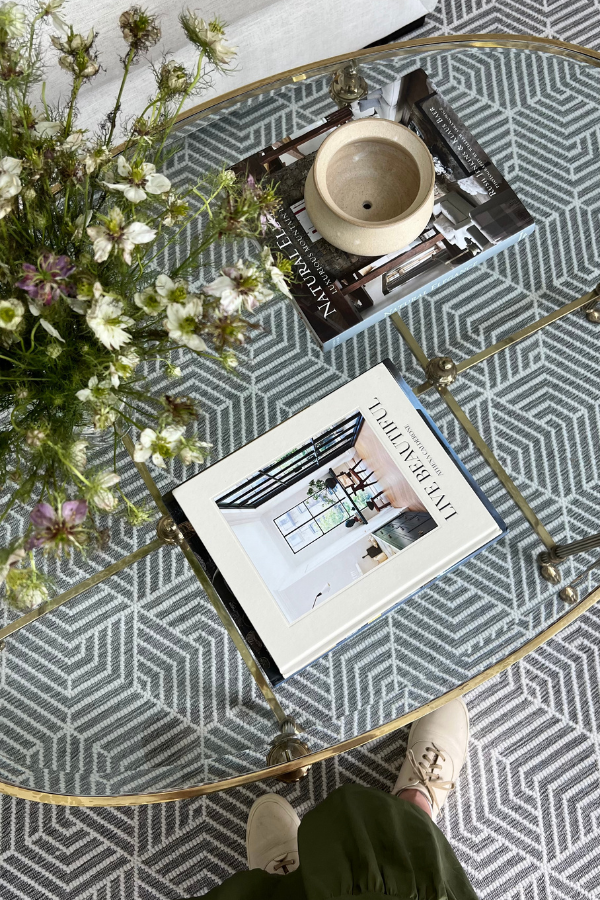 a clear glass table with flowers, two books, and an incense vase